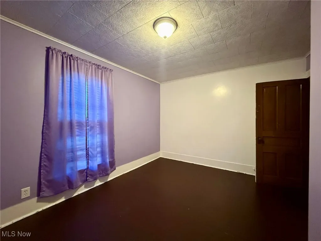 Bedroom with crown molding and dark wood-type flooring