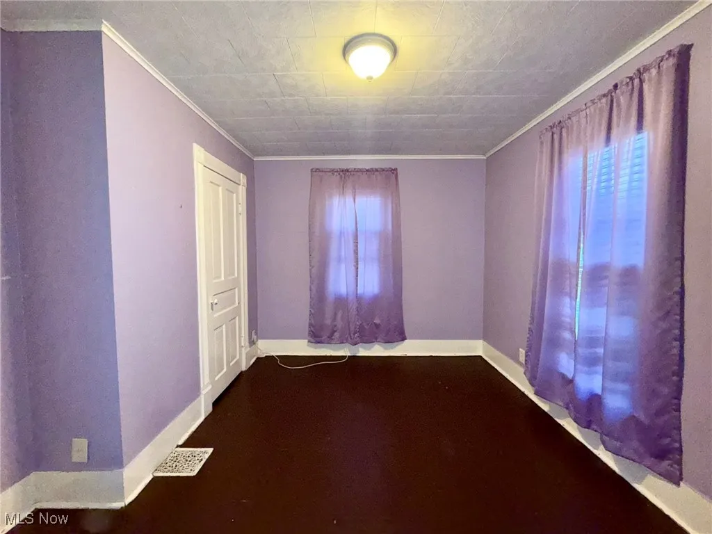 Bedroom with crown molding and dark wood-type flooring