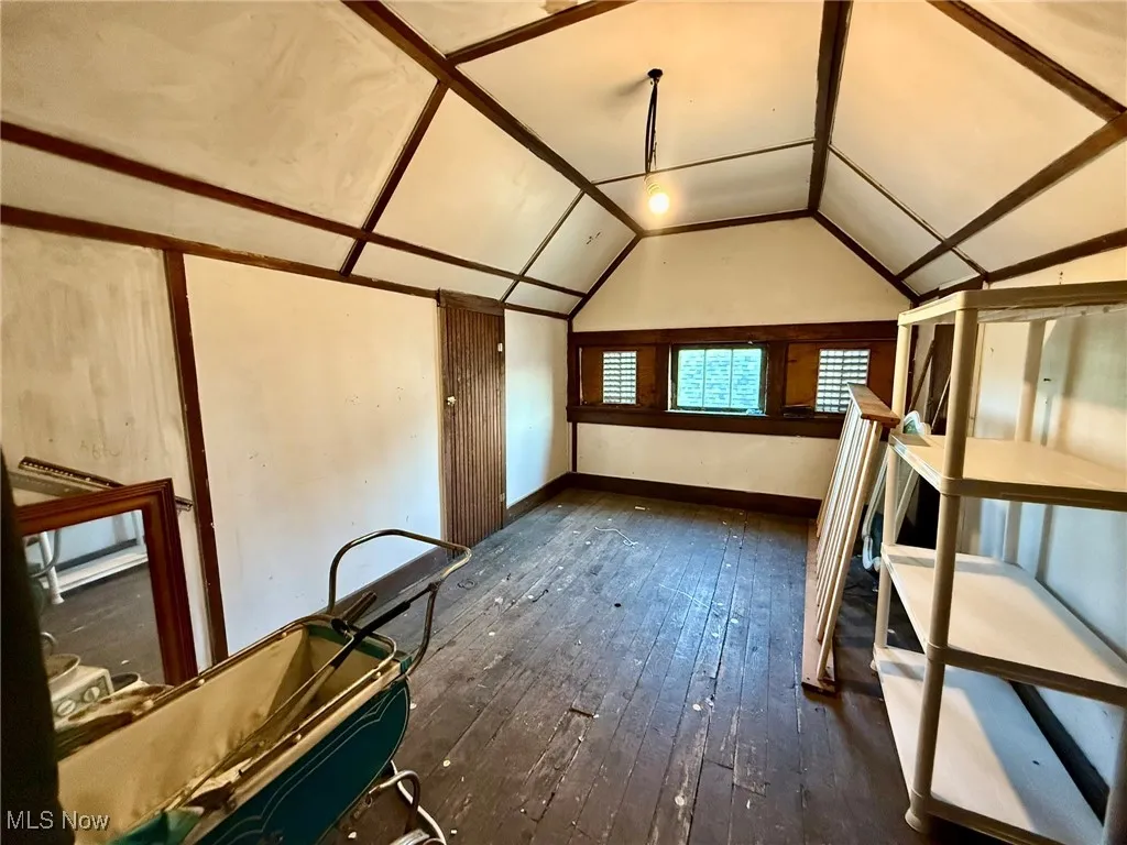 Additional living space in attic featuring dark wood-style flooring and vaulted ceiling