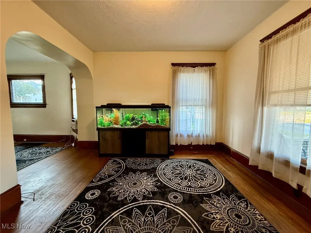 Dining room with arched walkways, wood finished floors, and a textured ceiling