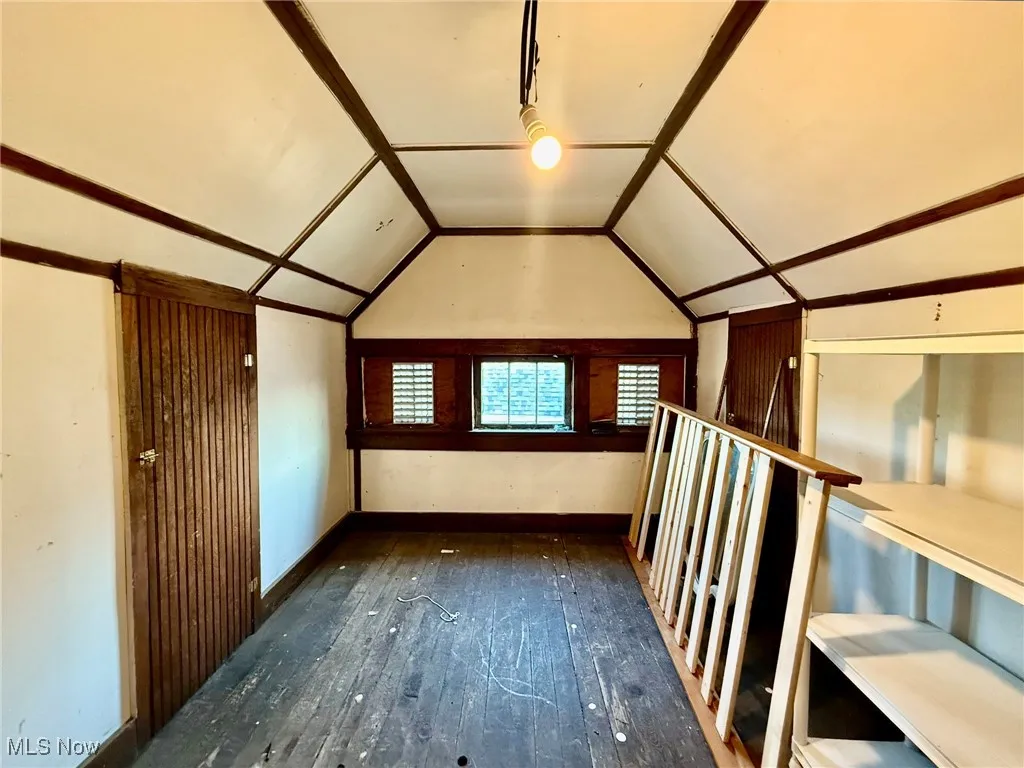 Additional living space in attic featuring dark wood-style flooring and vaulted ceiling