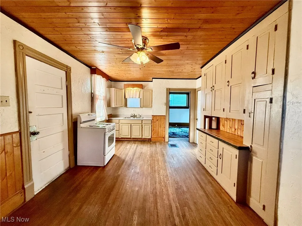 Kitchen featuring white electric range oven, dark wood-style floors, wood ceiling, wooden counters, and wainscoting