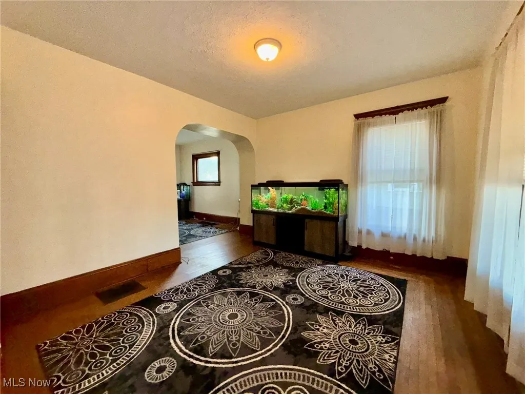 Dining room with arched walkways, wood finished floors, and a textured ceiling