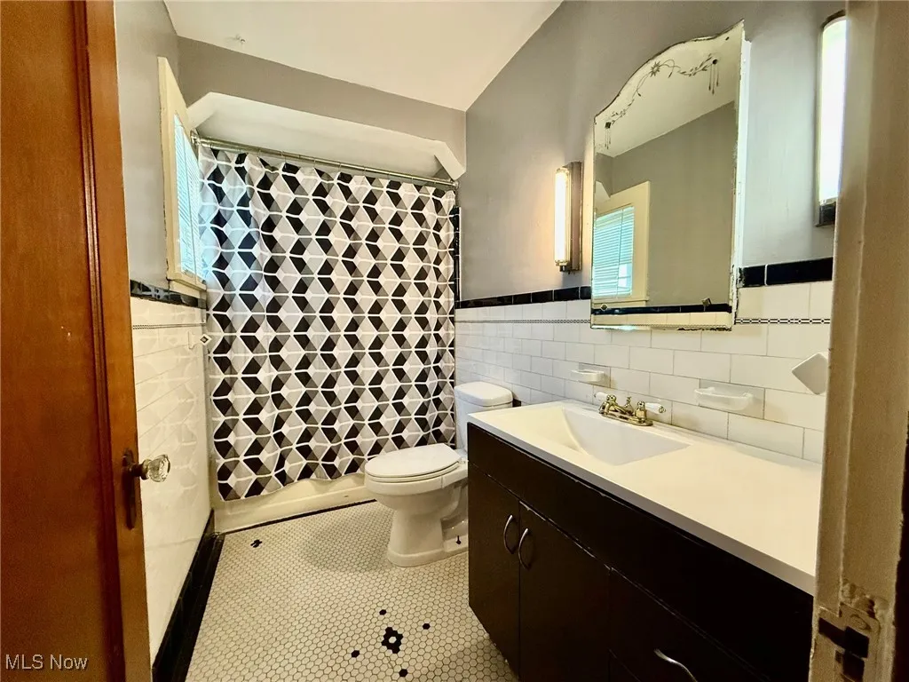 Bathroom featuring light tile patterned floors, vanity, tile walls, and a shower with curtain