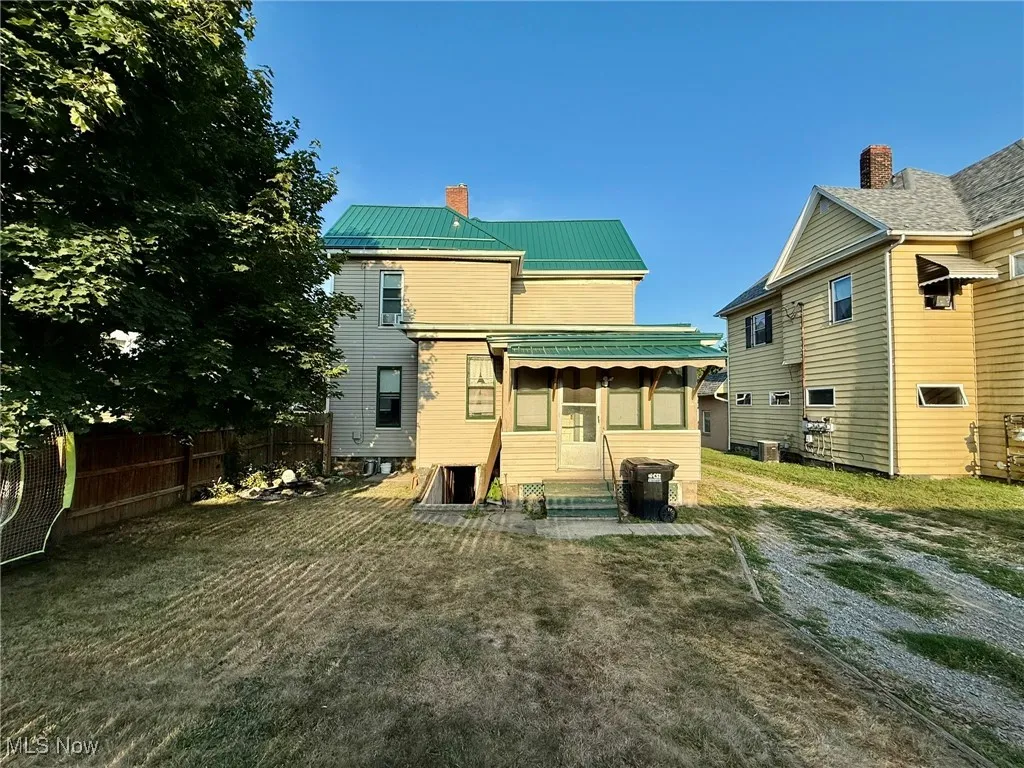 Back of property featuring a metal roof, a chimney, and a sunroom