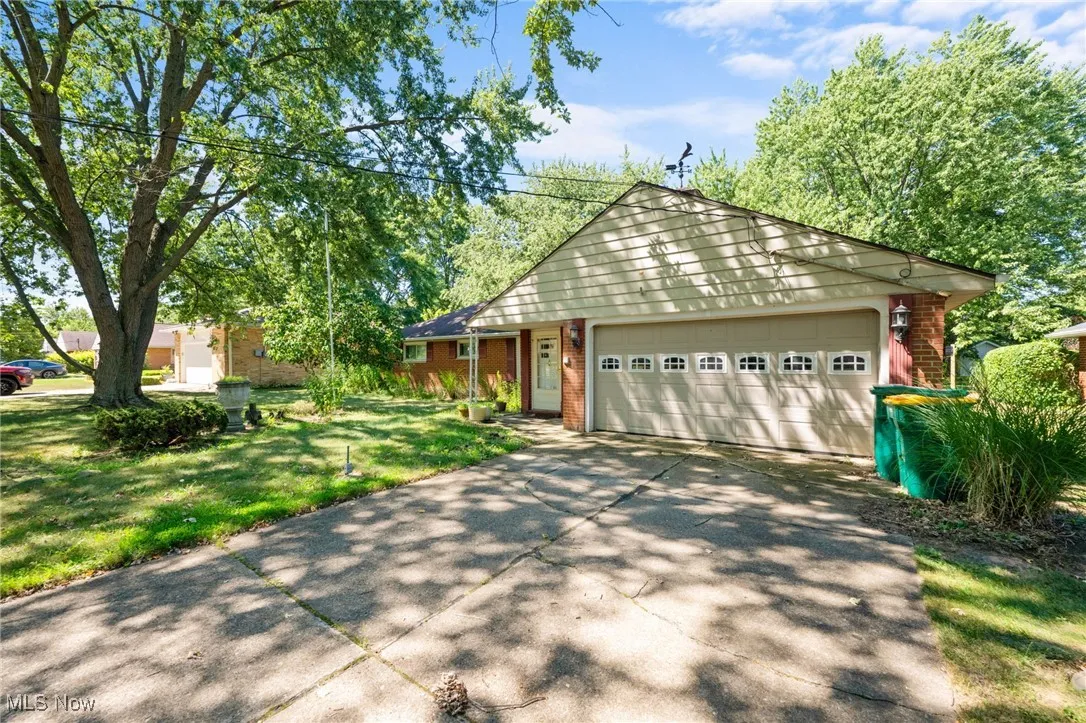 View of front of house featuring brick siding, concrete driveway, a garage, and a front lawn