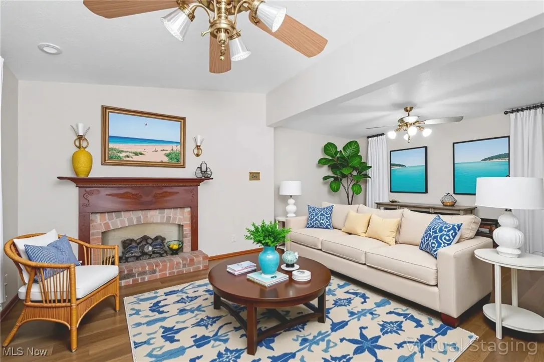 Living area featuring wood finished floors, ceiling fan, and a fireplace