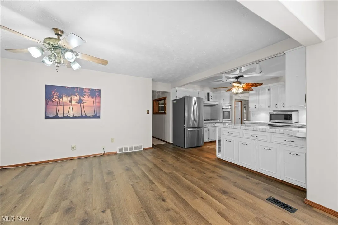 Kitchen with a ceiling fan, white cabinetry, and stainless steel appliances