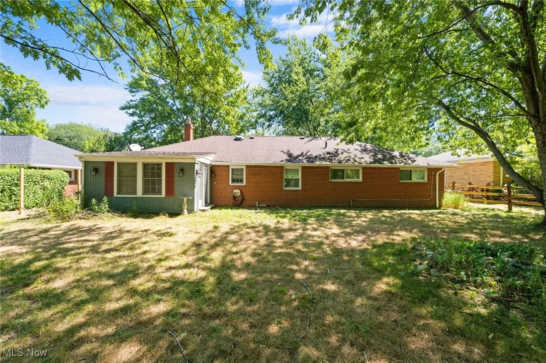 Back of house featuring a chimney, brick siding, and a lawn