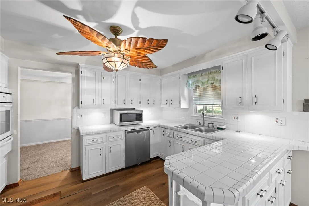 Kitchen featuring tile countertops, white cabinetry, a peninsula, and dark wood-type flooring