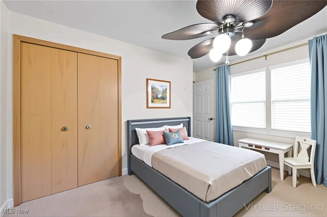 Carpeted bedroom featuring ceiling fan and a closet
