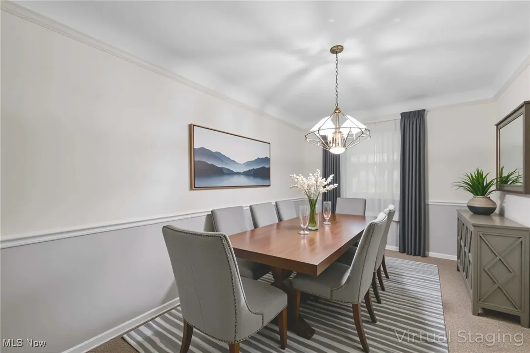 Carpeted dining room with ornamental molding and a chandelier