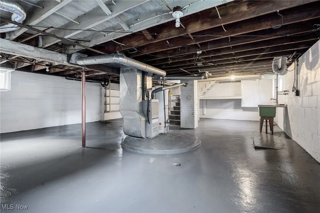 Basement featuring stairs, heating unit, and gas water heater