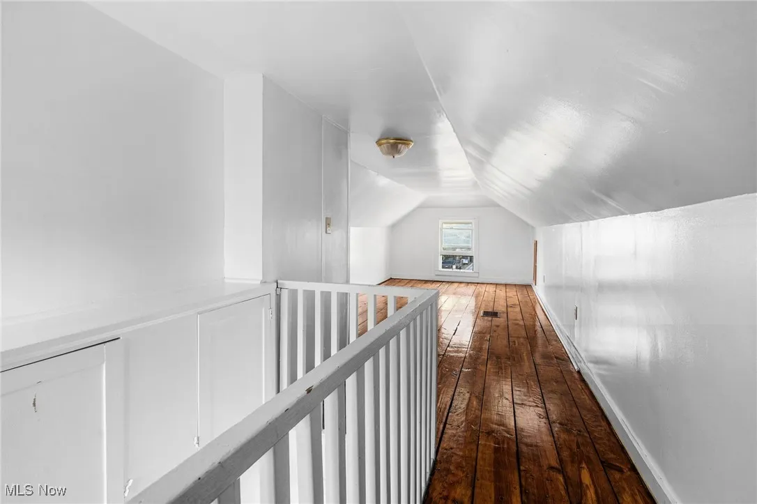 Corridor featuring dark wood-style floors and vaulted ceiling
