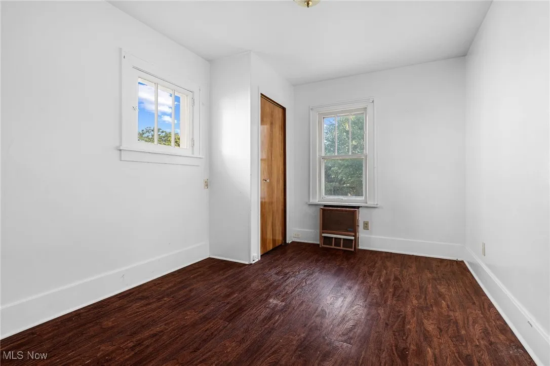 Unfurnished bedroom featuring dark wood finished floors and baseboards