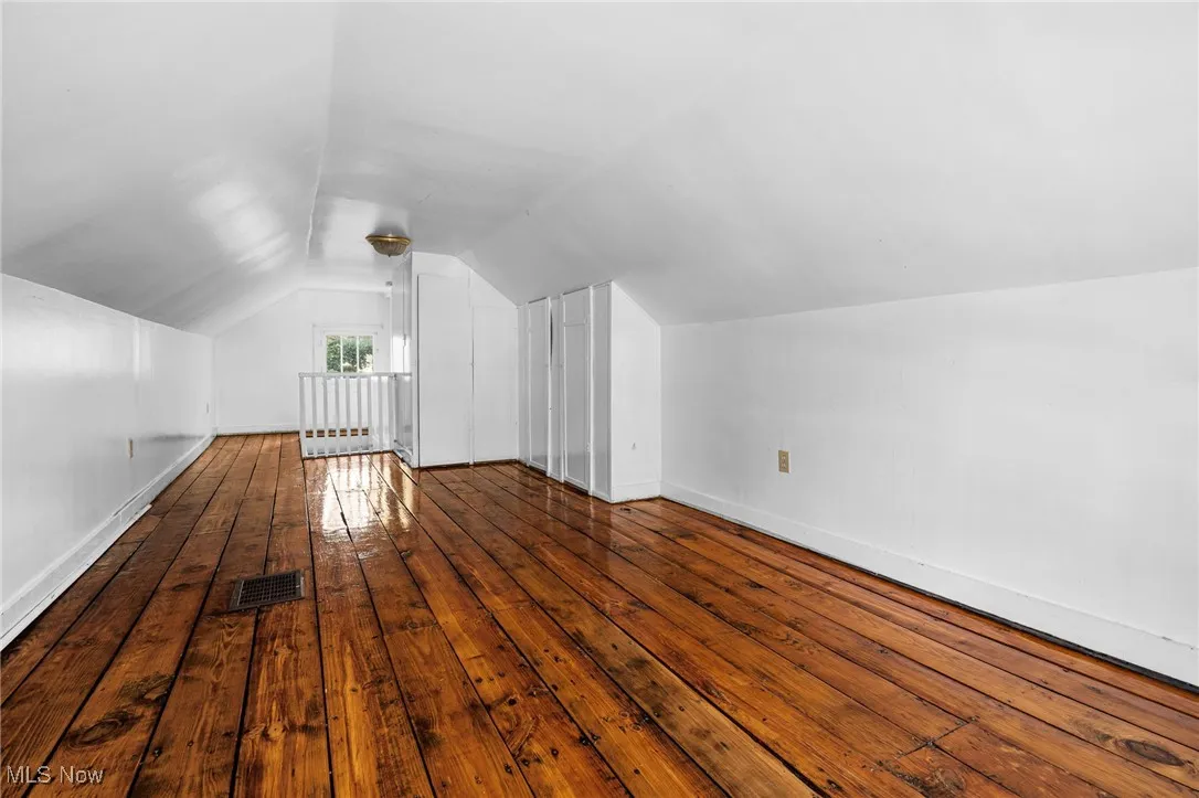 Bonus room with dark wood-style flooring and lofted ceiling