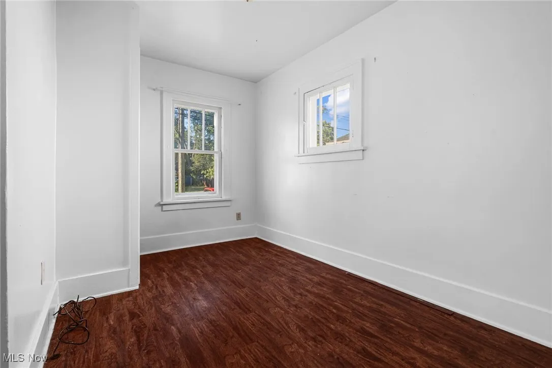 Spare room featuring dark wood finished floors and baseboards