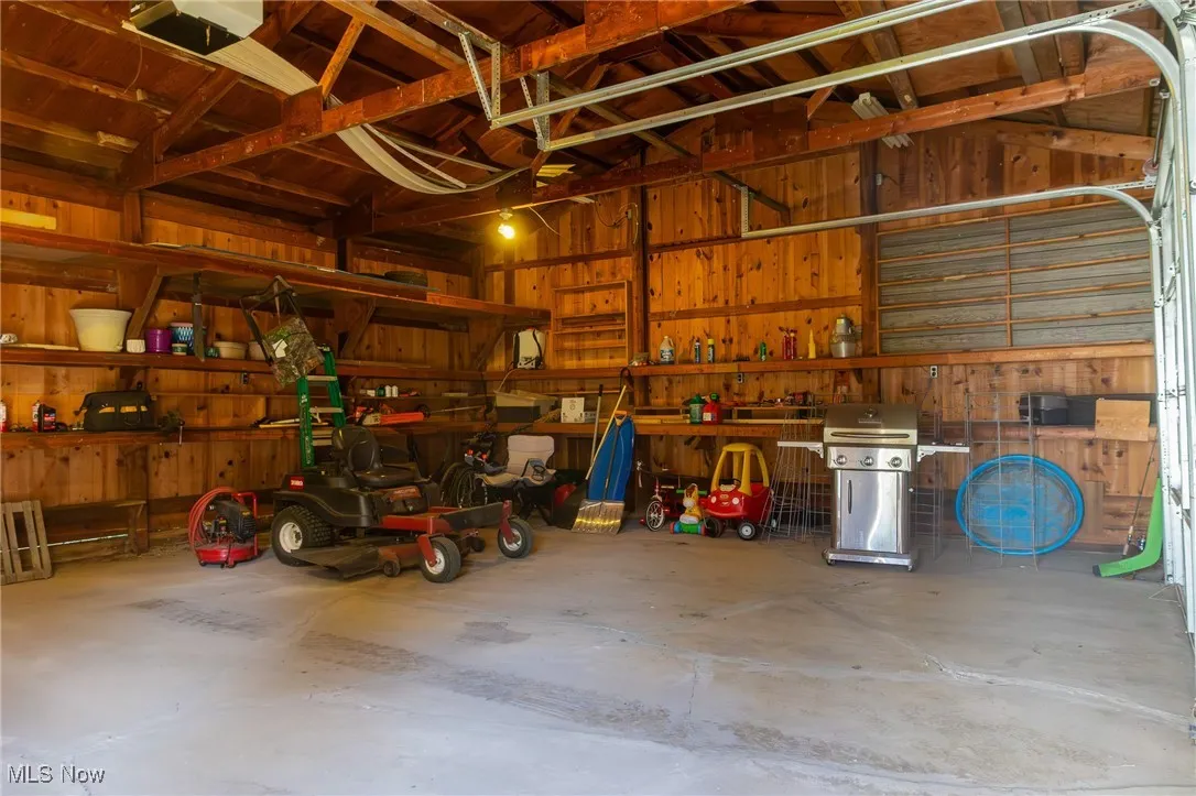 Garage featuring a garage door opener, a workshop area, and wood walls