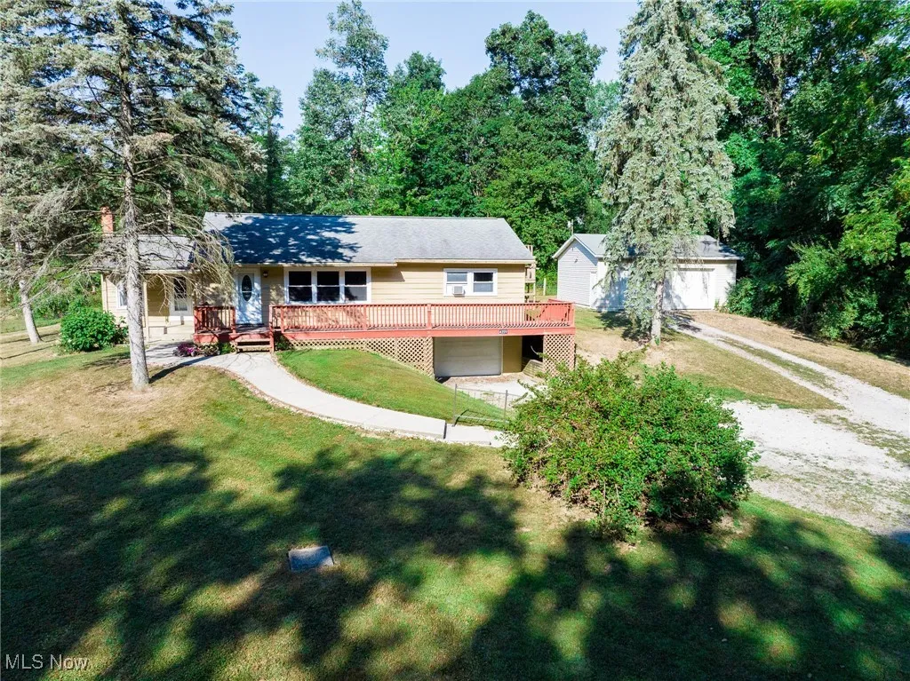 View of front of house featuring a garage, driveway, a front lawn, an outdoor structure, and a deck