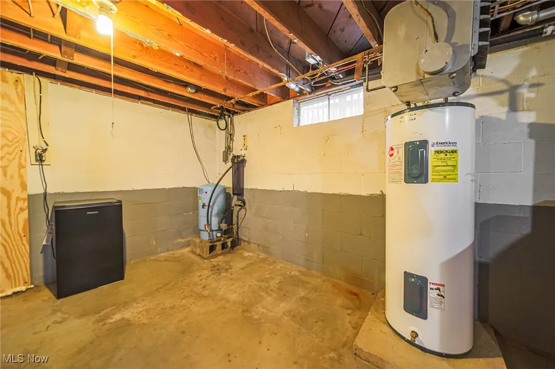 Below grade area featuring water heater and a water pressure tank