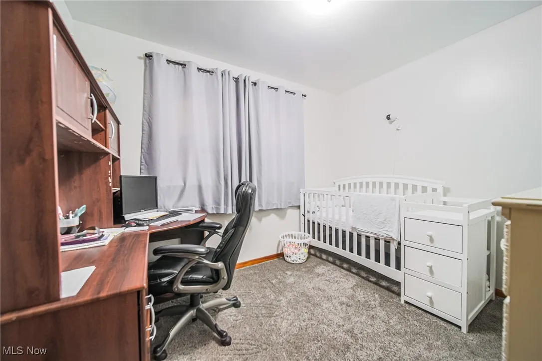Bedroom featuring a nursery area, an office area, and light colored carpet