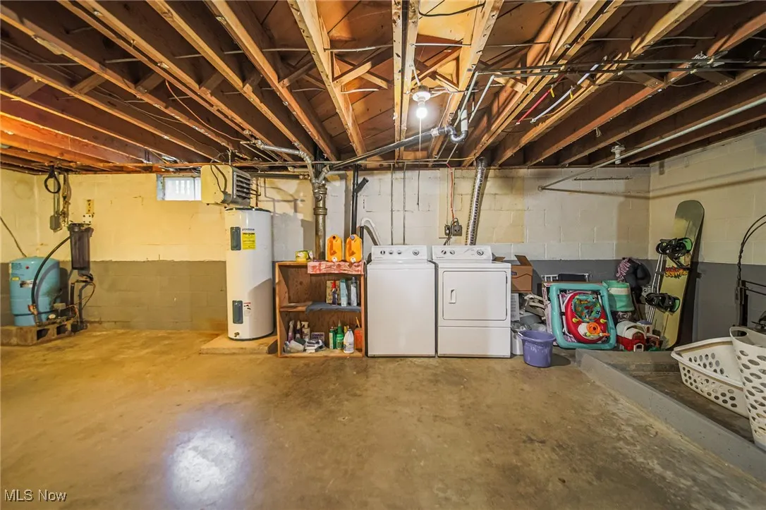 Below grade area with a water pressure tank, electric water heater, and separate washer and dryer