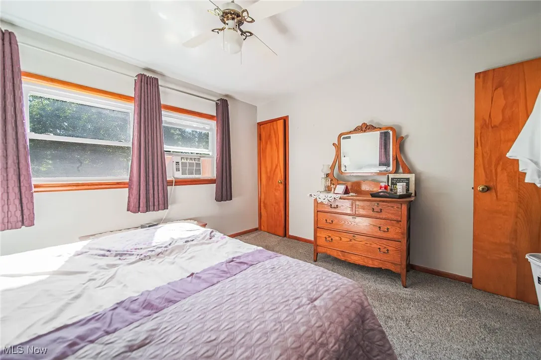 Carpeted bedroom with ceiling fan and cooling unit