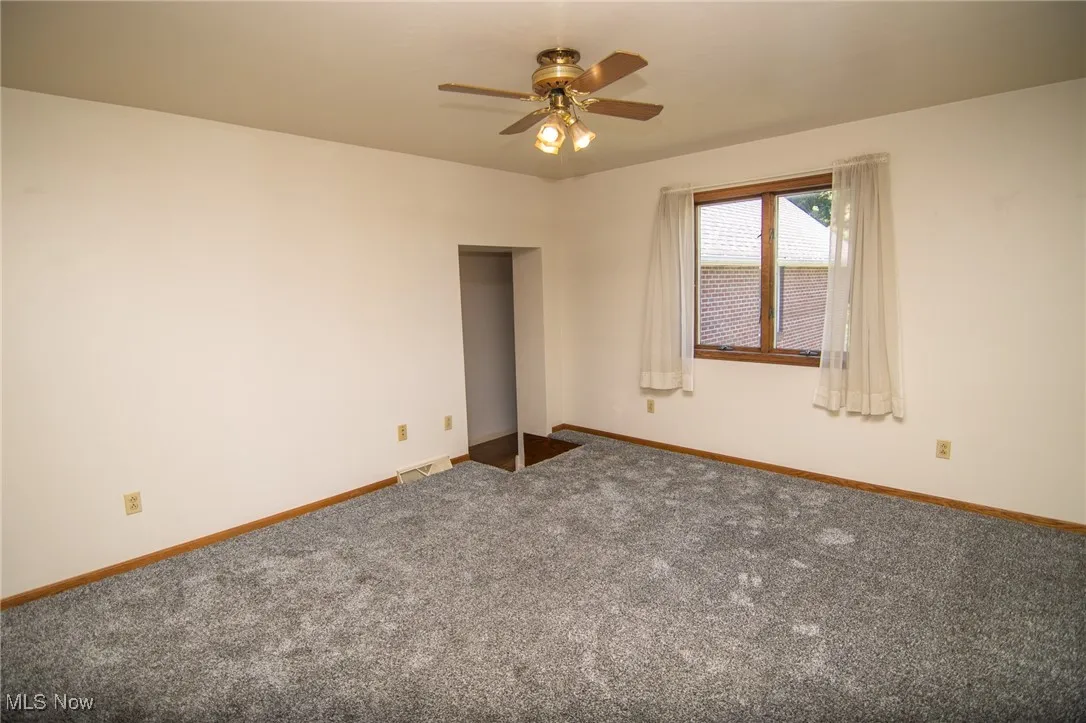 Carpeted spare room featuring baseboards and a ceiling fan