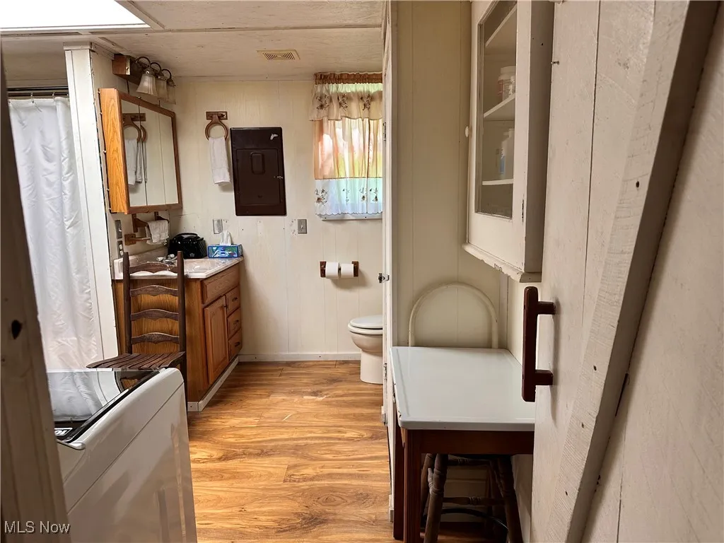 Bathroom with light wood-style floors, vanity, washer / dryer, wooden walls, and a shower with shower curtain