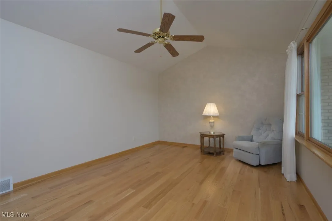 Unfurnished room featuring lofted ceiling, light wood-style flooring, and a ceiling fan