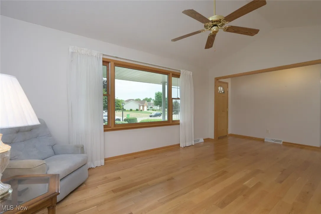 Sitting room featuring light wood finished floors, vaulted ceiling, and ceiling fan