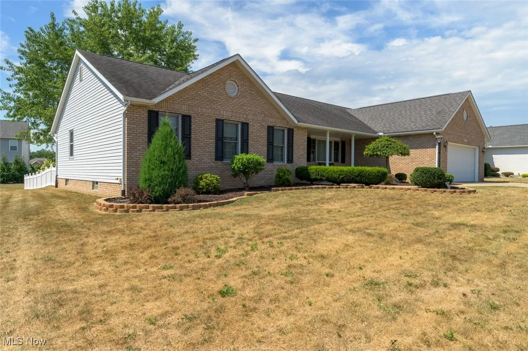 Ranch-style home featuring an attached garage, covered porch, a front lawn, and a shingled roof