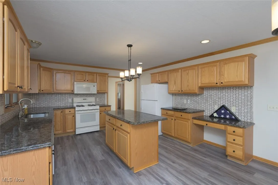 Kitchen featuring white appliances, backsplash, ornamental molding, pendant lighting, and dark wood-style flooring