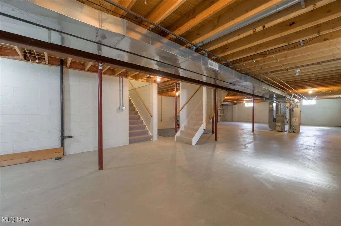 Unfinished below grade area with stairs, water heater, and heating unit