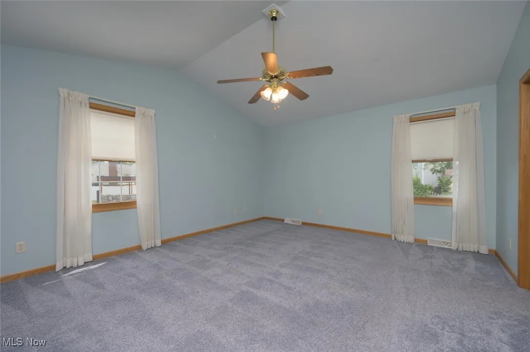 Unfurnished room featuring lofted ceiling, carpet, and ceiling fan