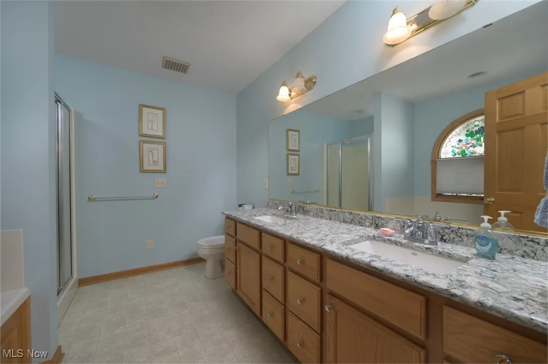 Bathroom featuring double vanity, a shower stall, and a garden tub