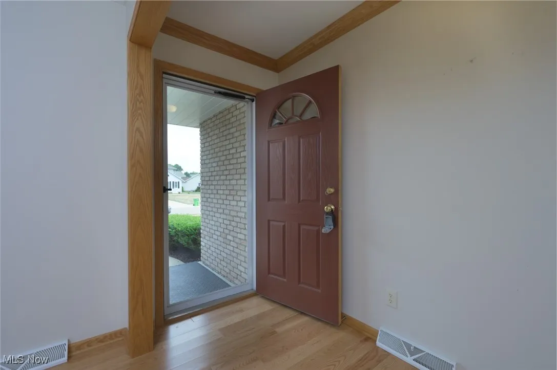 Entryway with ornamental molding and light wood-style flooring