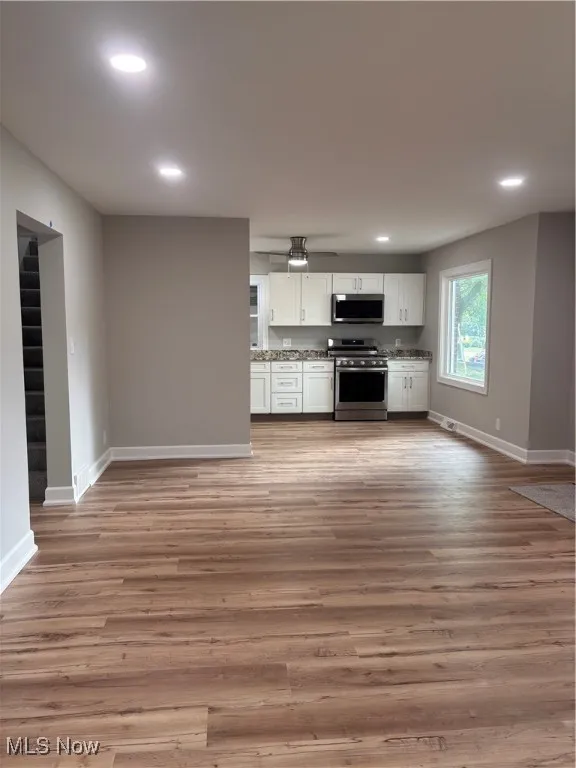 Kitchen featuring white cabinets, range, light wood-style flooring, recessed lighting, and open floor plan
