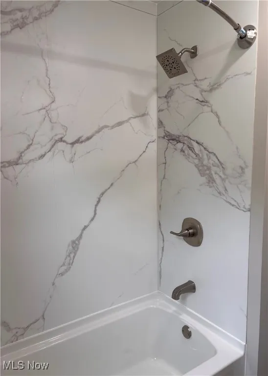 Bathroom featuring a combined bath / shower with marble appearance