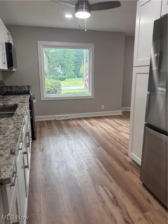Kitchen featuring white cabinetry, refrigerator, range, white microwave, and light wood-type flooring
