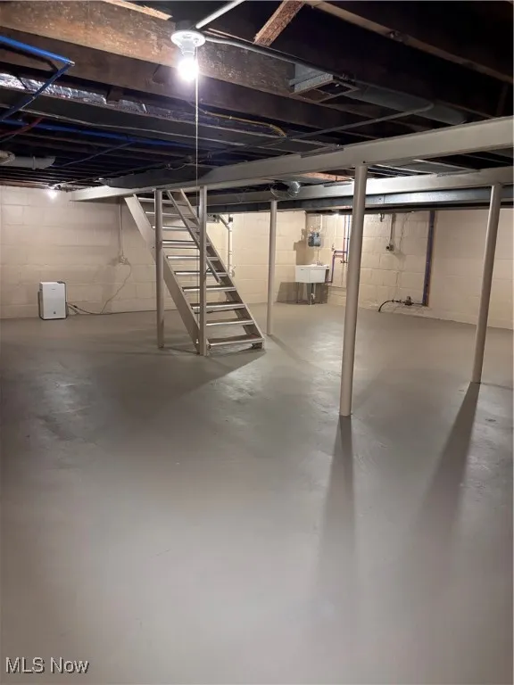 Unfinished basement featuring stairway and a sink