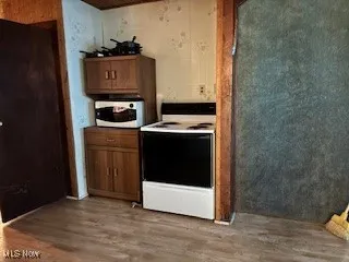 Kitchen with white appliances, light wood-style floors, and brown cabinetry