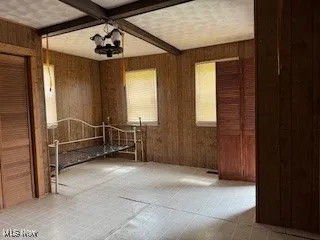 Spare room featuring wood walls and beam ceiling