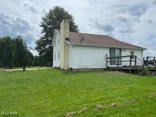 Rear view of property with a lawn, a chimney, and a deck