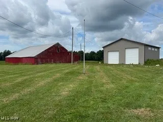 View of green lawn featuring an outbuilding and a detached garage
