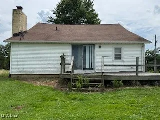Rear view of property with a wooden deck, a lawn, and a chimney