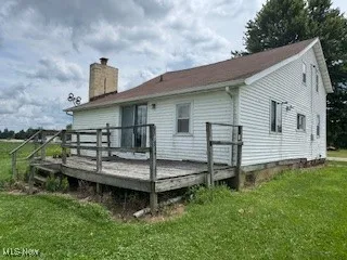 Rear view of house with a lawn, a chimney, and a deck