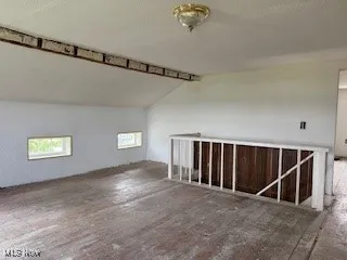 Additional living space with vaulted ceiling and a textured ceiling