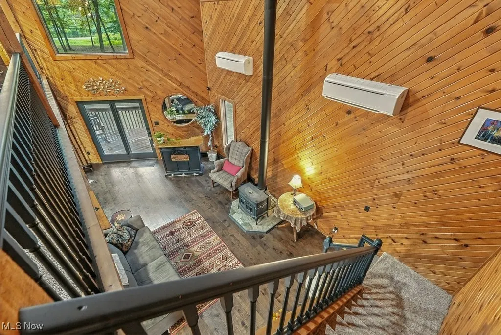 Staircase with a wood stove, a high ceiling, wooden walls, and wood finished floors