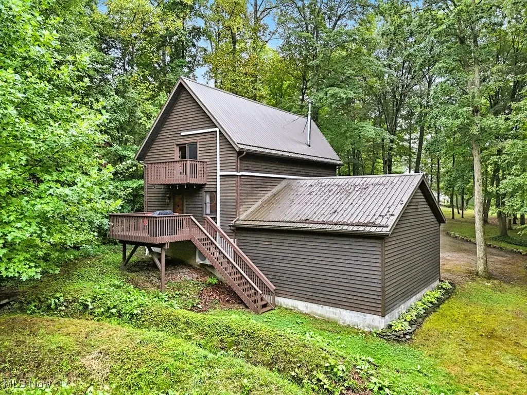 Rear view of property with a metal roof, stairway, a deck, and view of wooded area